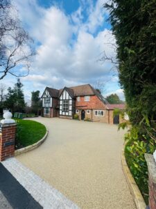 Resin bound driveway in warm beige finish with curved brick edging at traditional Tudor-style home