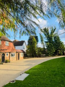 Large resin bound driveway in warm beige finish at traditional Tudor-style property with landscaped lawn