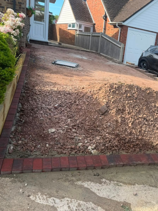New driveway sub-base preparation with brick edging and sleeper retaining border.